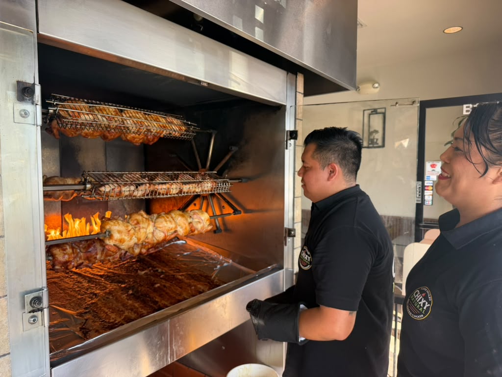Chixy Natural team beside the flame-broiled chicken rotisserie